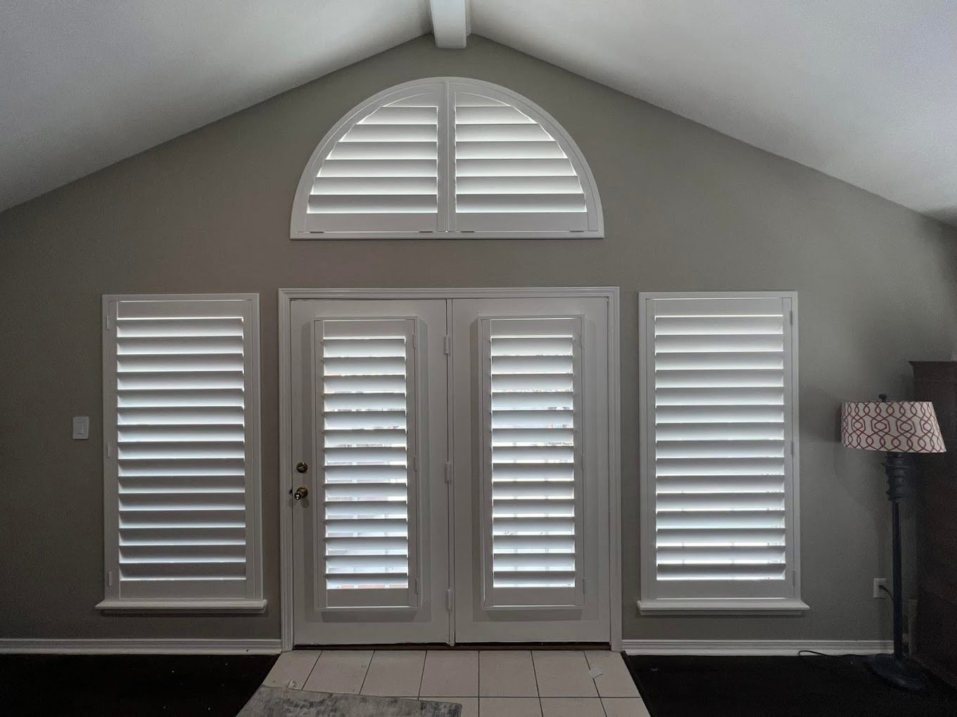 Arched plantation shutters over French doors